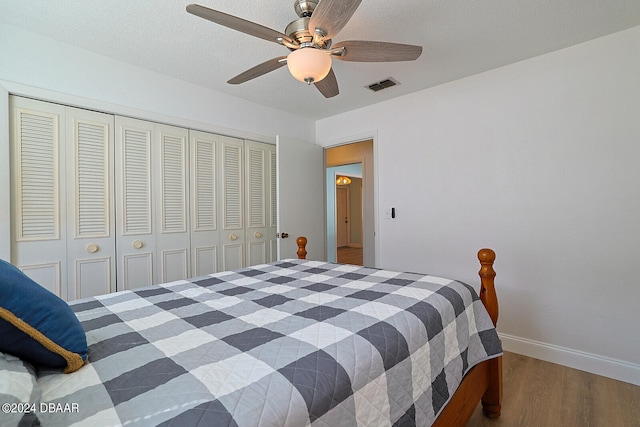 bedroom with a closet, hardwood / wood-style flooring, and ceiling fan