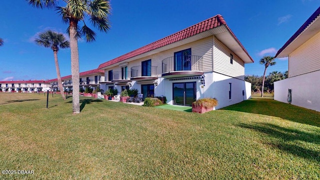 back of property with a lawn and a balcony