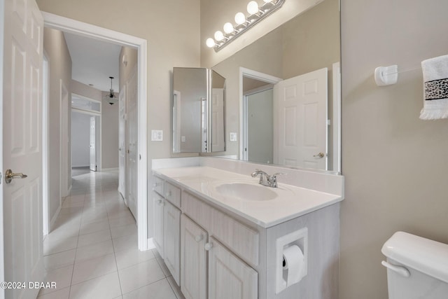 bathroom with toilet, vanity, and tile patterned flooring