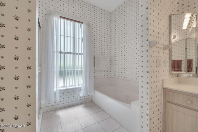 bathroom with a tub to relax in, vanity, and tile patterned flooring