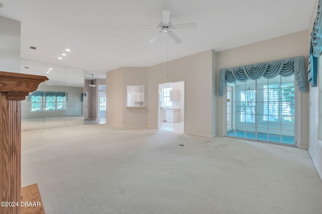 unfurnished living room with plenty of natural light, light carpet, and ceiling fan