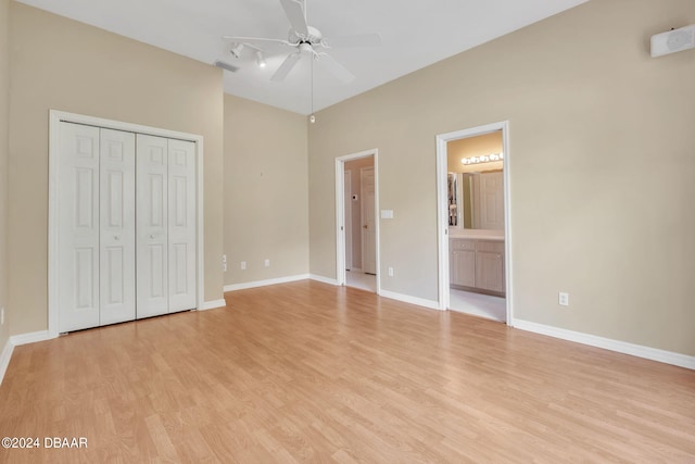 unfurnished bedroom featuring ensuite bathroom, ceiling fan, a closet, and light wood-type flooring