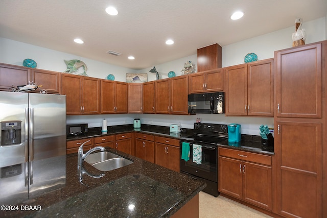 kitchen featuring dark stone countertops, sink, and black appliances