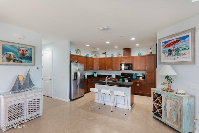 kitchen featuring black appliances, a kitchen breakfast bar, sink, light tile patterned floors, and an island with sink