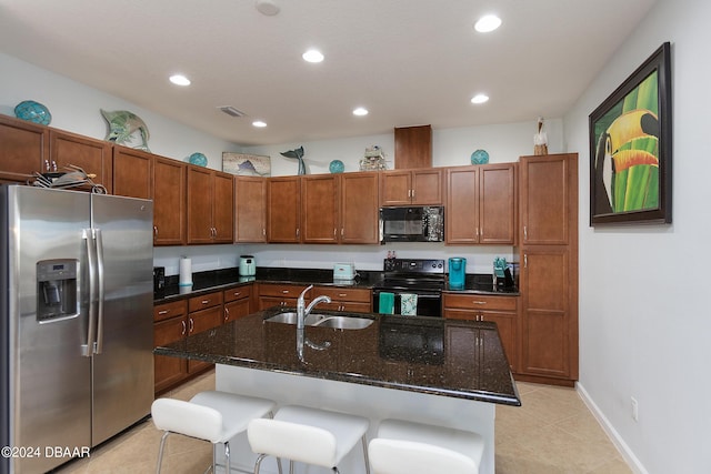 kitchen featuring a kitchen breakfast bar, sink, a kitchen island with sink, and black appliances