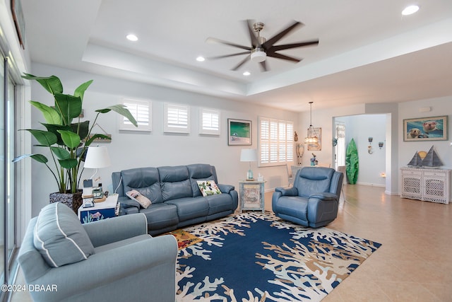 tiled living room featuring ceiling fan and a raised ceiling