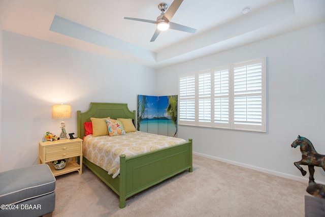 bedroom with a tray ceiling, ceiling fan, and light carpet