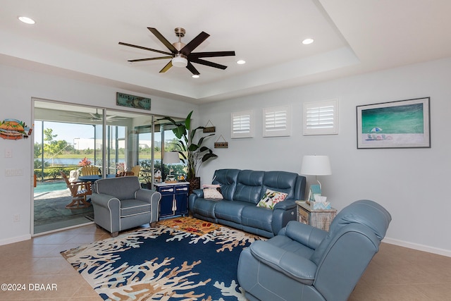 tiled living room with a raised ceiling and ceiling fan