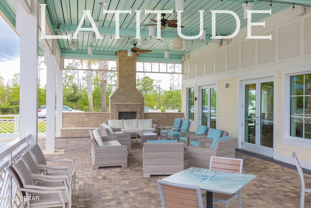 view of patio with an outdoor living space with a fireplace, ceiling fan, and french doors