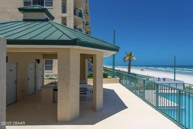 view of patio / terrace featuring a water view and a beach view