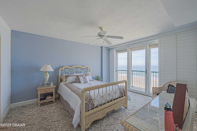 carpeted bedroom featuring ceiling fan, access to outside, a textured ceiling, and a water view