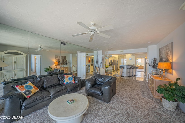 living room with ceiling fan, a textured ceiling, and carpet