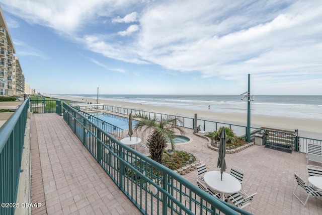 balcony featuring a water view, a beach view, and a patio