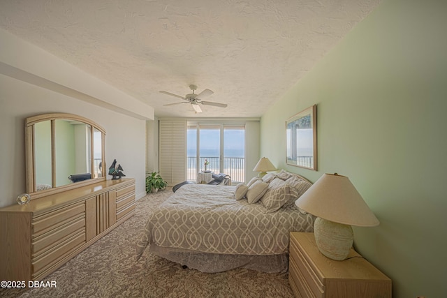 bedroom featuring ceiling fan, carpet, a textured ceiling, and a water view