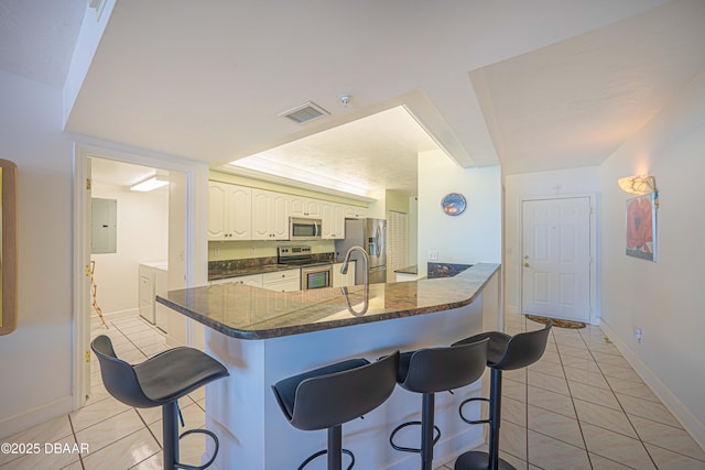 kitchen featuring washing machine and dryer, appliances with stainless steel finishes, a kitchen breakfast bar, and kitchen peninsula