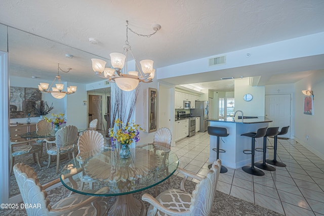 dining area with an inviting chandelier, sink, a textured ceiling, and light tile patterned floors