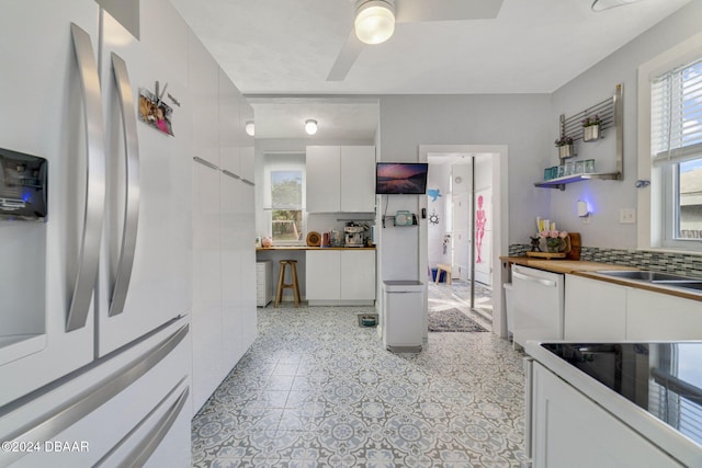 kitchen with white appliances, backsplash, white cabinets, sink, and ceiling fan