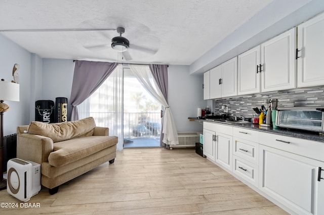 interior space with sink, tasteful backsplash, ceiling fan, white cabinetry, and light hardwood / wood-style flooring