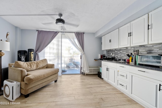 1233 S Atlantic Ave Unit 2230, Daytona Beach, FL 32118 - kitchen with a ceiling fan, dark countertops, white cabinetry, light wood-type flooring, and a sink