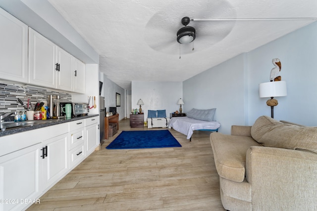 living room featuring sink, ceiling fan, a textured ceiling, and light hardwood / wood-style floors