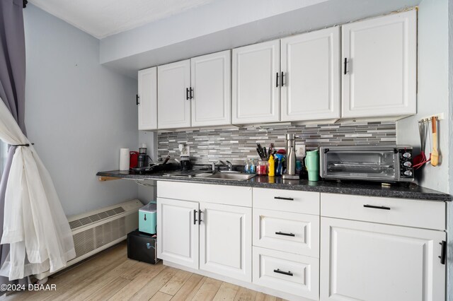 kitchen featuring white cabinets, light hardwood / wood-style floors, sink, and backsplash