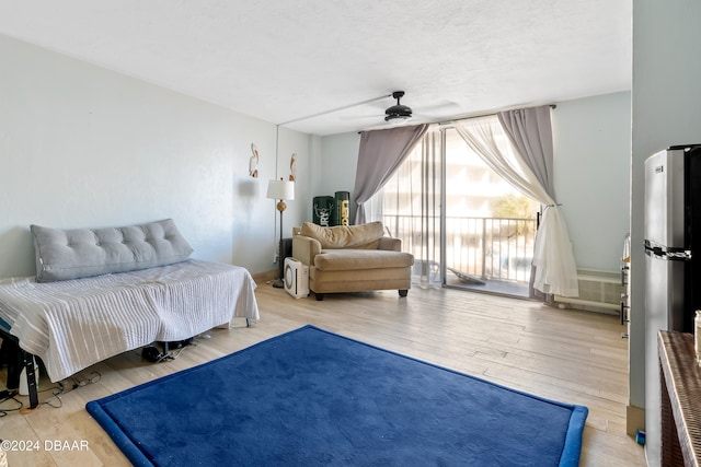 bedroom with hardwood / wood-style flooring, ceiling fan, and stainless steel fridge