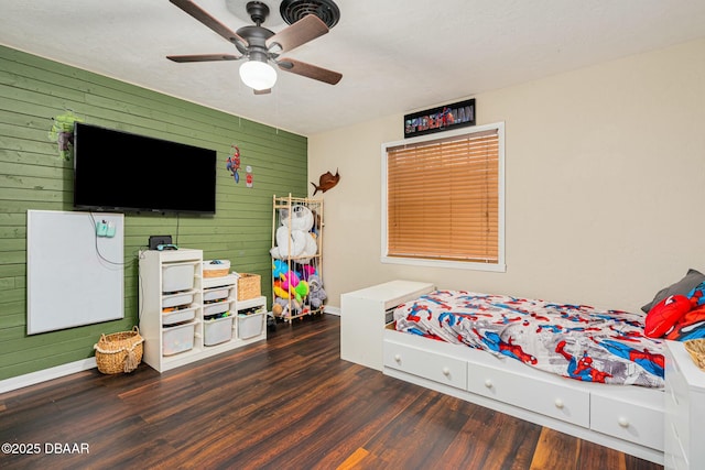 bedroom with a textured ceiling, dark hardwood / wood-style floors, ceiling fan, and wood walls