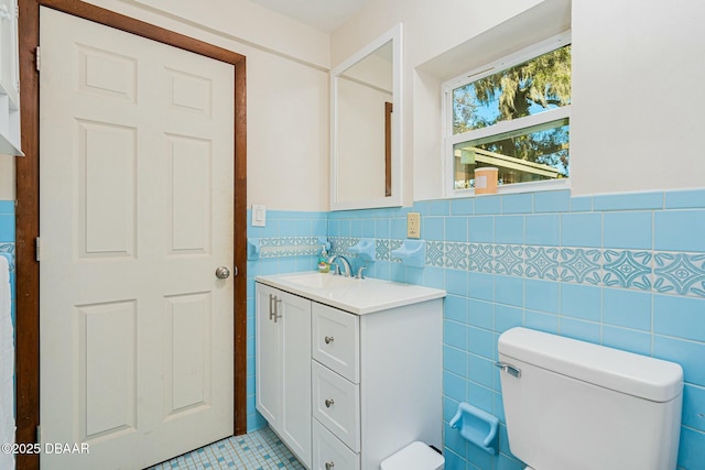 bathroom with tile patterned floors, vanity, toilet, and tile walls