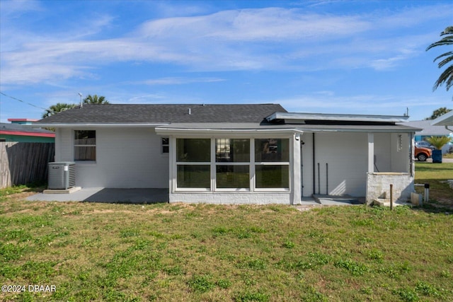 rear view of house with central air condition unit and a yard