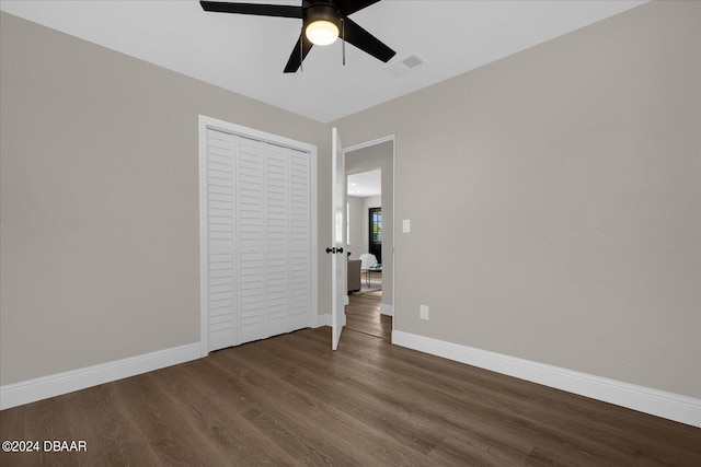 unfurnished bedroom with dark hardwood / wood-style flooring, ceiling fan, and a closet