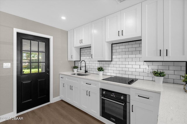 kitchen with dark hardwood / wood-style flooring, black electric stovetop, sink, light stone countertops, and stainless steel oven