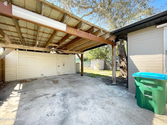 garage with an attached carport, a storage unit, and fence