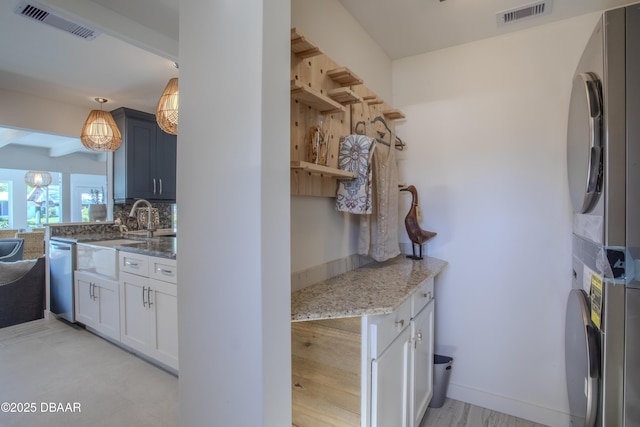 1076 Shockney Dr, Ormond Beach, FL 32174 - kitchen featuring stacked washer / drying machine, a sink, light stone countertops, stainless steel dishwasher, and decorative backsplash