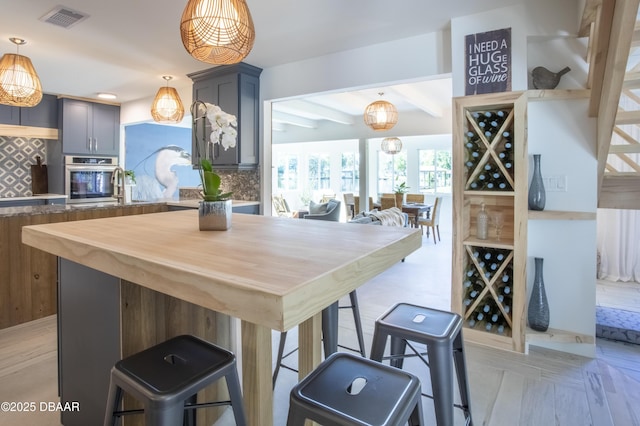 1076 Shockney Dr, Ormond Beach, FL 32174 - kitchen featuring stainless steel oven, decorative backsplash, a kitchen breakfast bar, pendant lighting, and beam ceiling