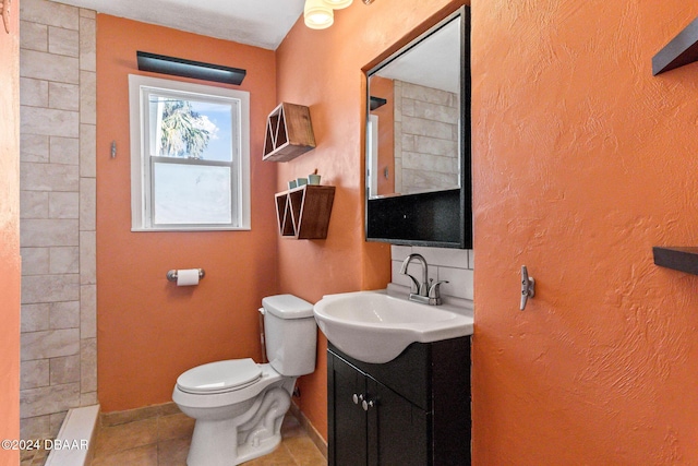 bathroom featuring tile patterned floors, vanity, toilet, and a tile shower