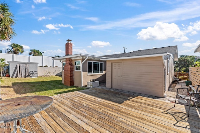 deck with a storage shed and a lawn