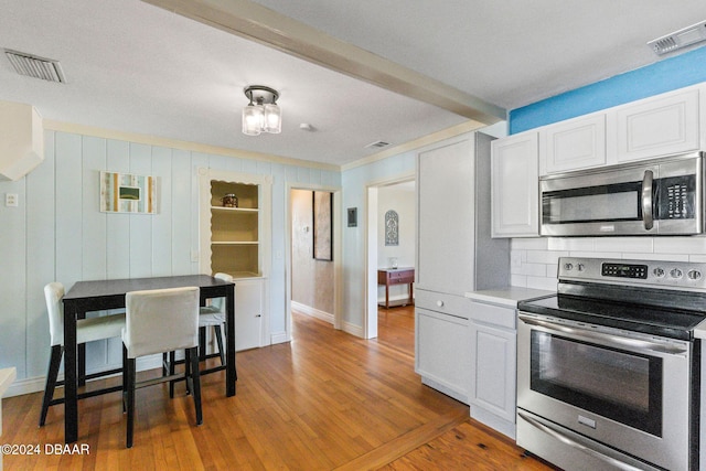 kitchen featuring decorative backsplash, white cabinetry, stainless steel appliances, and wood-type flooring