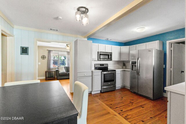 kitchen with white cabinets, appliances with stainless steel finishes, dark hardwood / wood-style flooring, and tasteful backsplash