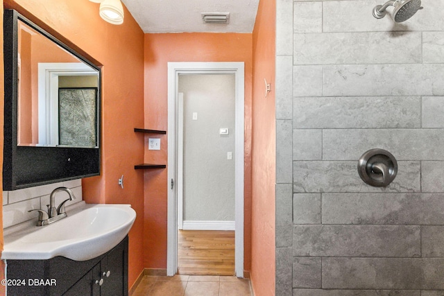 bathroom with tile patterned floors, vanity, tiled shower, and a textured ceiling