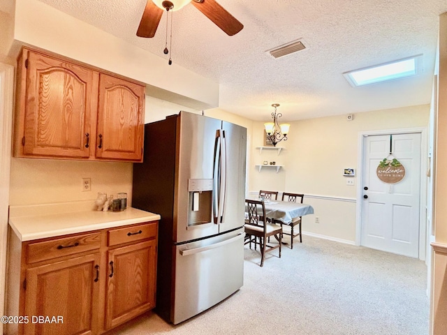 146 Deer Lake Cir, Ormond Beach, FL 32174 - kitchen featuring stainless steel fridge with ice dispenser, a textured ceiling, brown cabinetry, a ceiling fan, and a chandelier