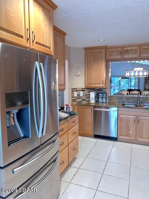 kitchen with backsplash, stainless steel appliances, light tile patterned floors, and sink