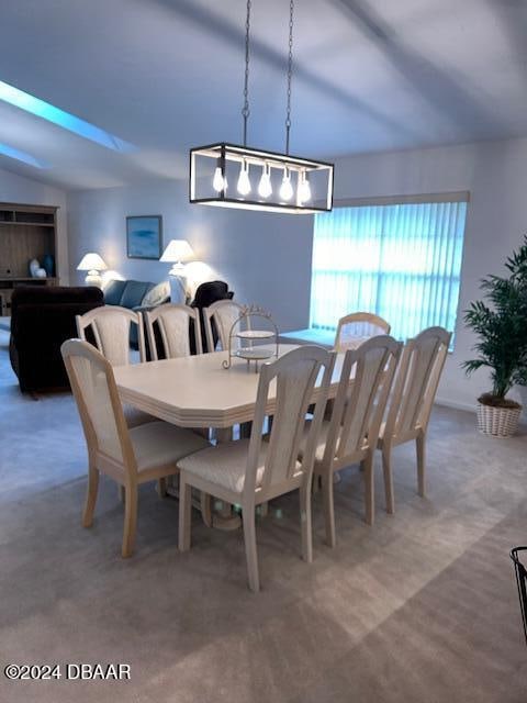 carpeted dining room featuring vaulted ceiling