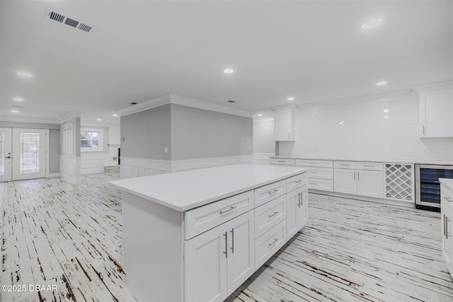 kitchen featuring crown molding, white cabinets, decorative backsplash, and beverage cooler