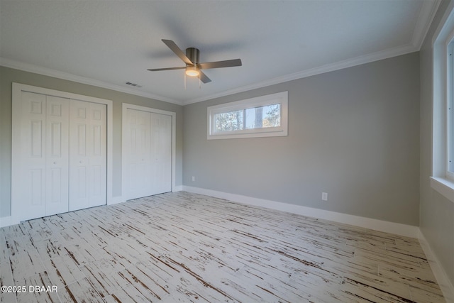 unfurnished bedroom with multiple closets, ceiling fan, light hardwood / wood-style flooring, and ornamental molding