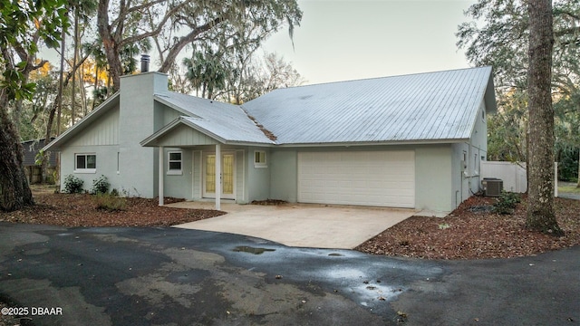 view of front of property featuring french doors, central AC unit, and a garage