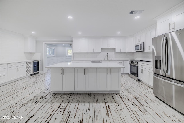 kitchen featuring a center island, white cabinetry, sink, stainless steel appliances, and wine cooler