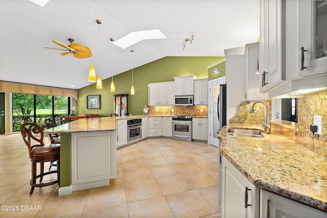 kitchen with sink, white cabinets, a kitchen breakfast bar, hanging light fixtures, and stainless steel appliances