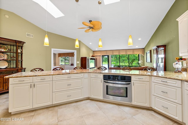 kitchen featuring light stone countertops, plenty of natural light, stainless steel oven, and white cabinets