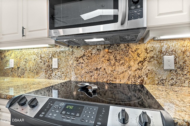 interior details with tasteful backsplash, appliances with stainless steel finishes, stone countertops, and white cabinets