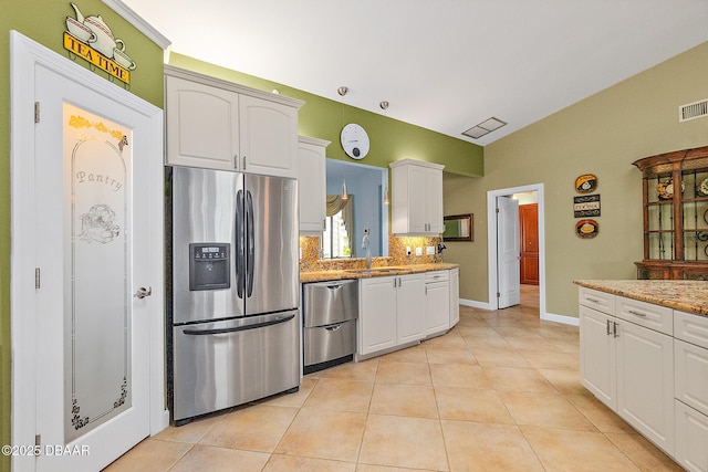 kitchen featuring light tile patterned floors, appliances with stainless steel finishes, white cabinetry, tasteful backsplash, and light stone countertops